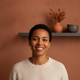 Happy customer, mid-30s, smiling confidently against a warm terracotta and charcoal background.