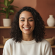 Smiling young woman in a bright white top, with a terracotta and burnt sienna background, conveying trust and satisfaction.